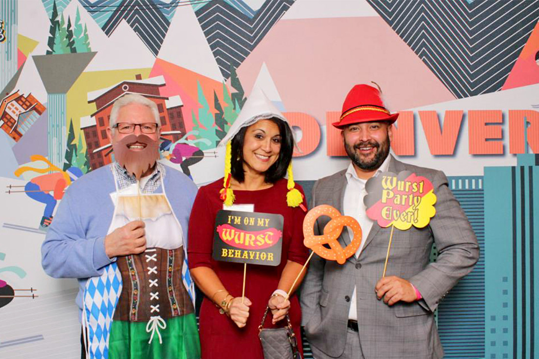 People posing with fun props in front of a fun background at a corporate event