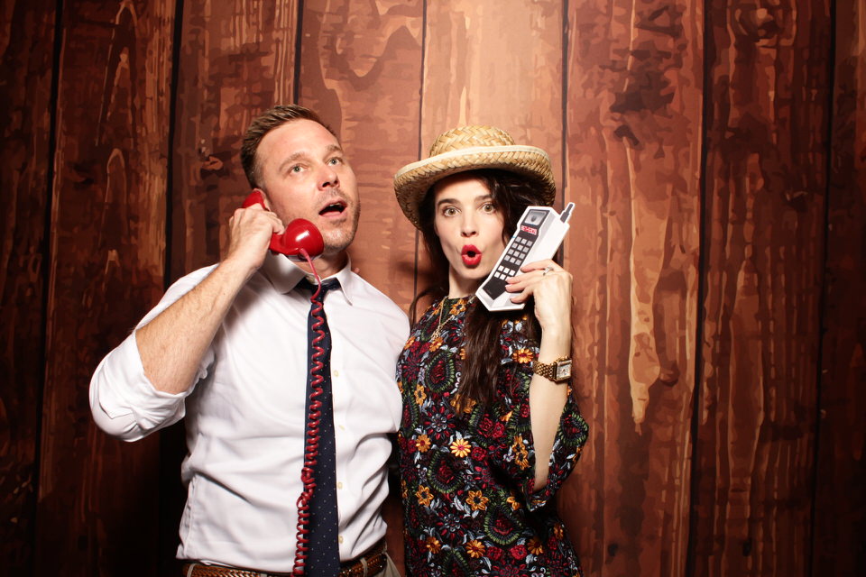 Rustic Colorado themed photo booth with people using vintage props
