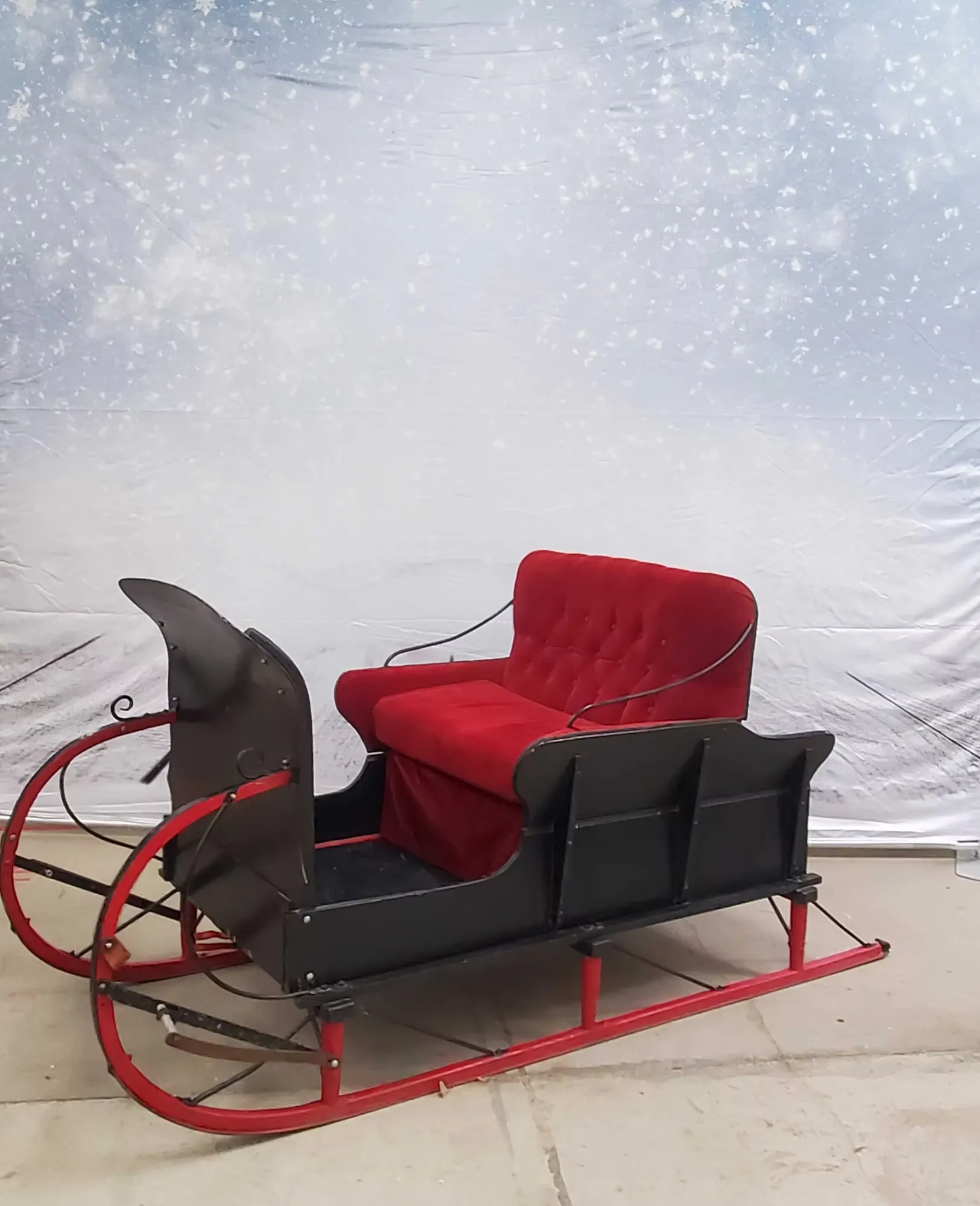 Winter-themed props for sleigh photo booth including fake snow, decorative trees, lanterns and snow jackets