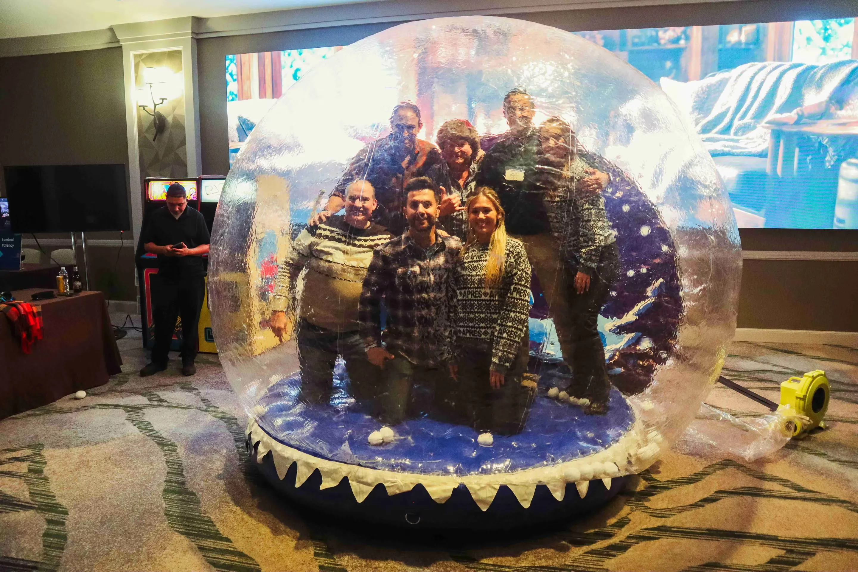 Interactive snow globe photo booth with guests bouncing and playing inside inflatable winter wonderland