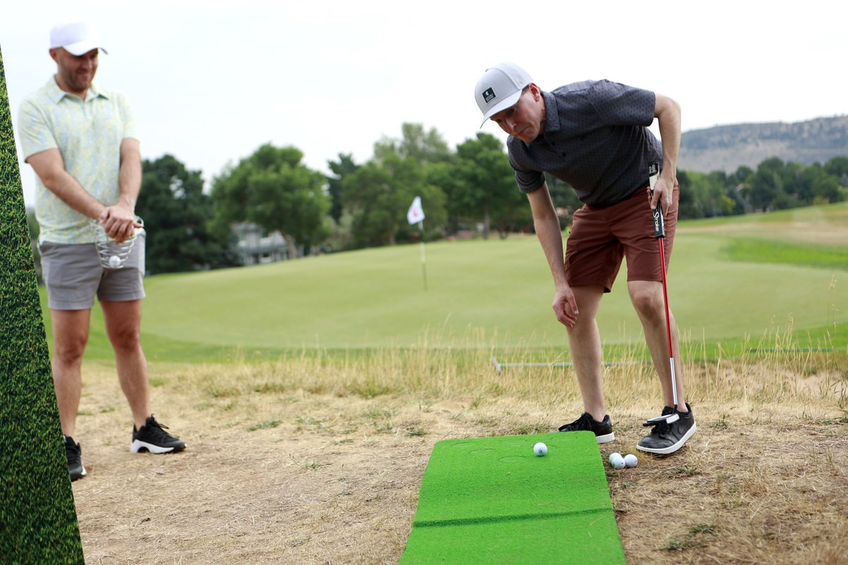 Two guests putting with course backdrop during MiHi Multi-Step Golf Championship near Denver.